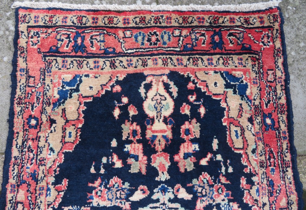 A long, narrow hand-knotted Persian Sarouk runner rug featuring a deep navy blue field, central floral medallions, and terracotta borders. View VI