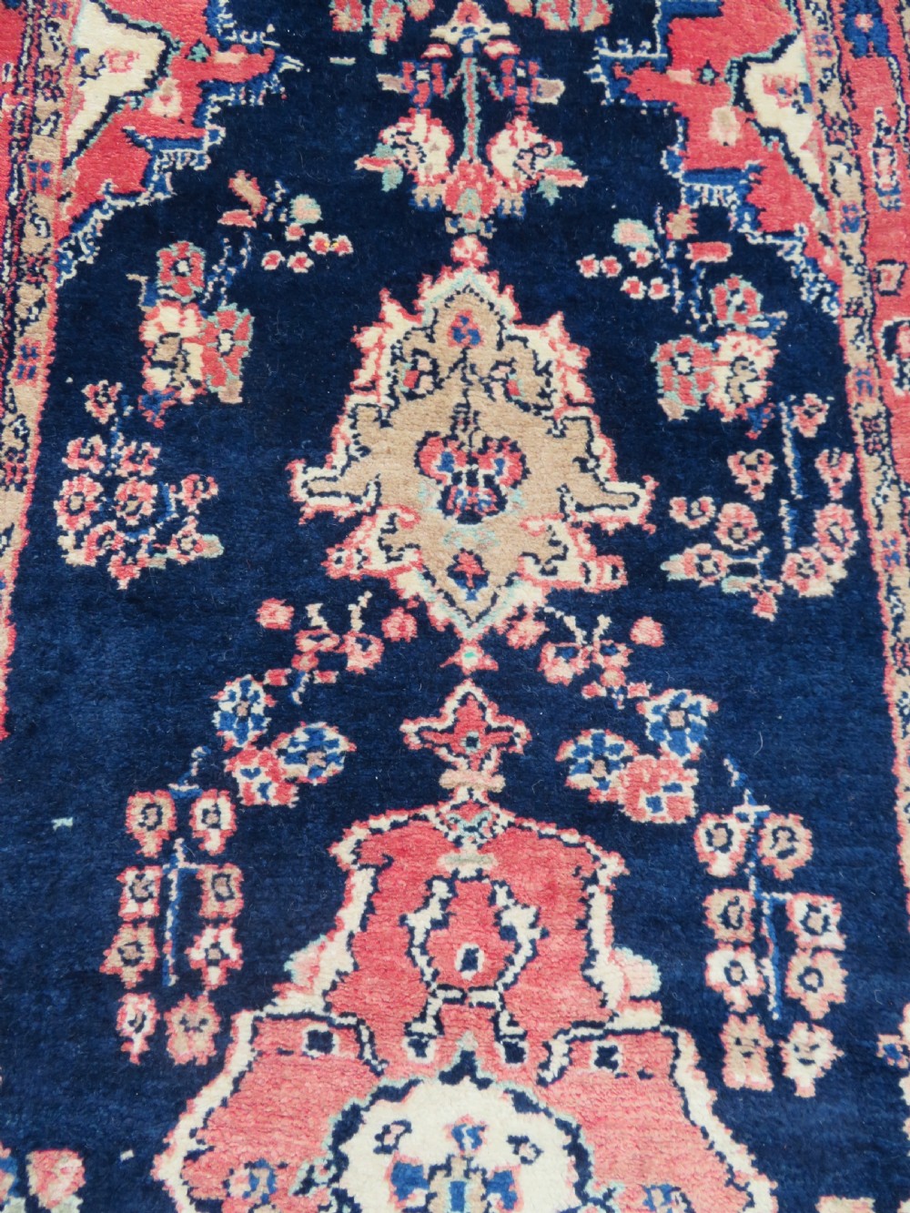 A long, narrow hand-knotted Persian Sarouk runner rug featuring a deep navy blue field, central floral medallions, and terracotta borders. View IX