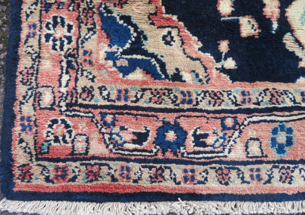 A long, narrow hand-knotted Persian Sarouk runner rug featuring a deep navy blue field, central floral medallions, and terracotta borders. View X