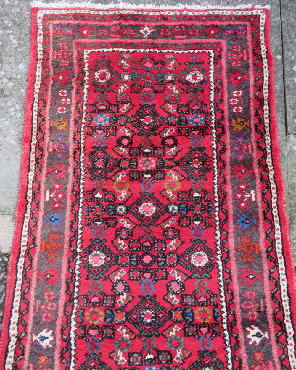 A long, narrow hand-knotted Persian Hamadan runner rug featuring a red field woven with geometric motifs and dark patterned borders. View III