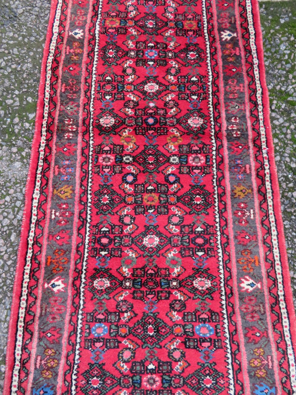 A long, narrow hand-knotted Persian Hamadan runner rug featuring a red field woven with geometric motifs and dark patterned borders. View V