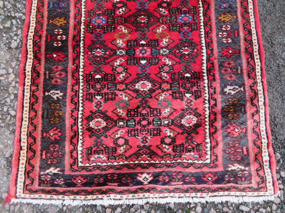 A long, narrow hand-knotted Persian Hamadan runner rug featuring a red field woven with geometric motifs and dark patterned borders. View VII