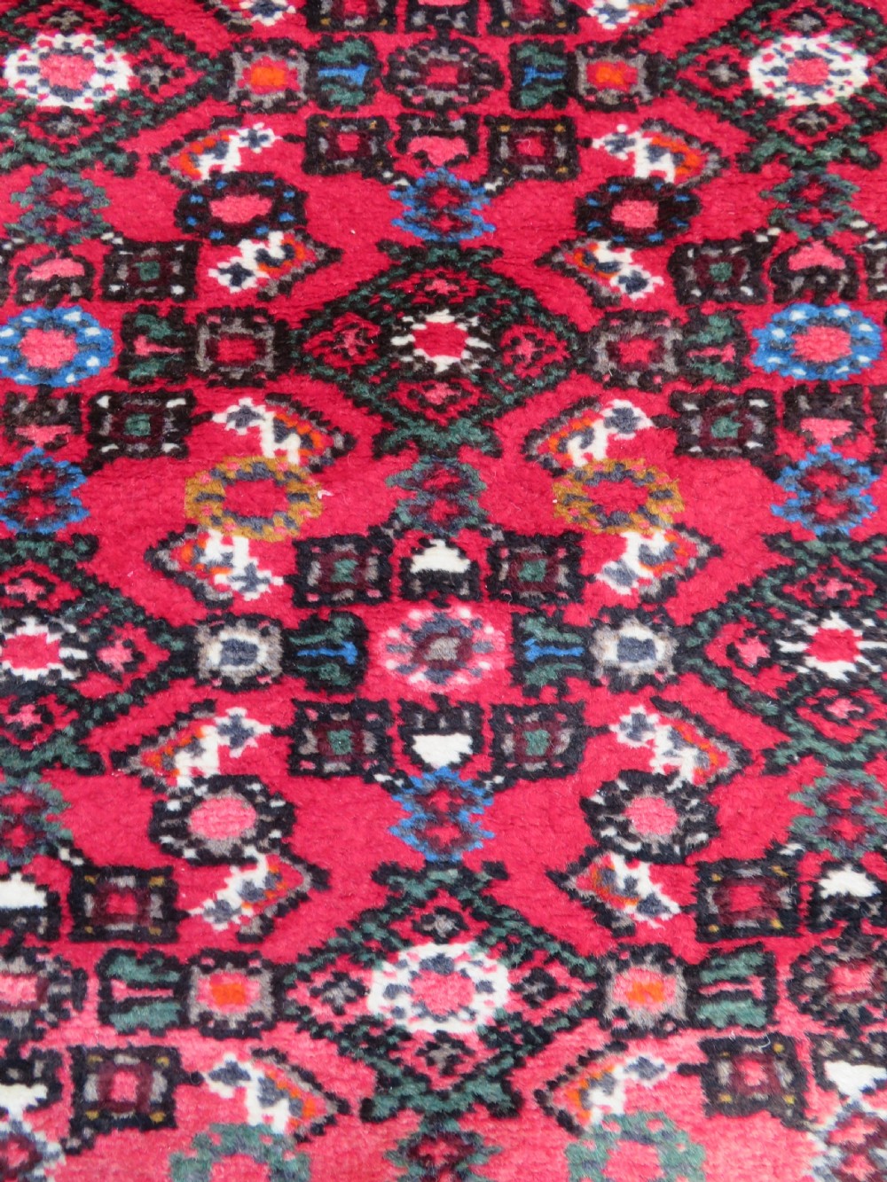 A long, narrow hand-knotted Persian Hamadan runner rug featuring a red field woven with geometric motifs and dark patterned borders. View X