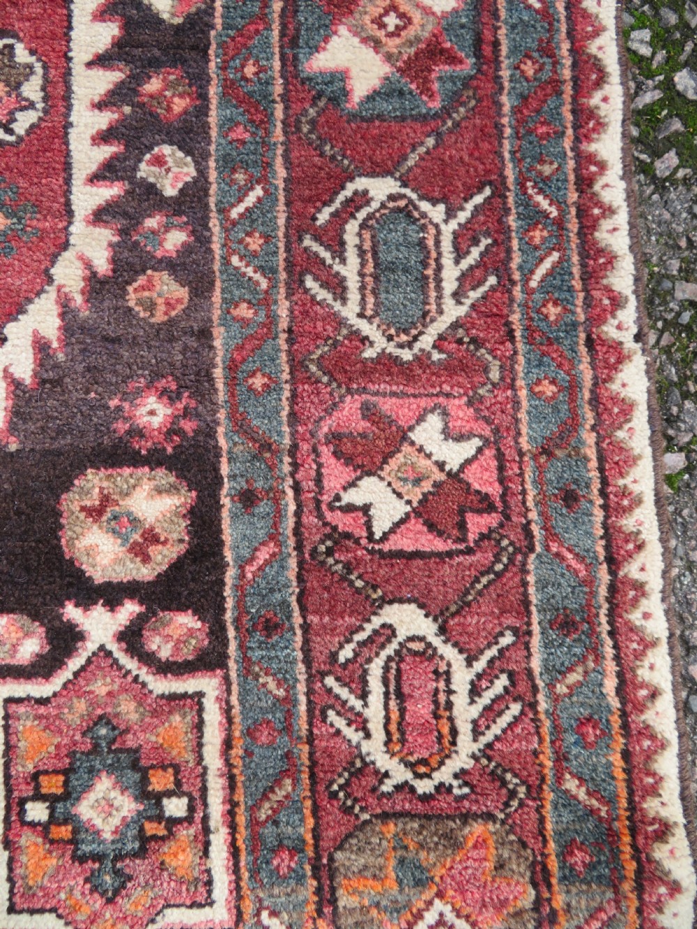 A rectangular hand-knotted North West Persian Kurdish wool rug featuring a central crimson diamond medallion surrounded by geometric motifs on a dark brown field with decorative borders. View VI
