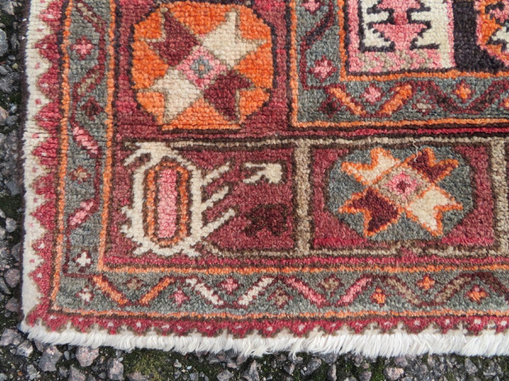 A rectangular hand-knotted North West Persian Kurdish wool rug featuring a central crimson diamond medallion surrounded by geometric motifs on a dark brown field with decorative borders. View VIII