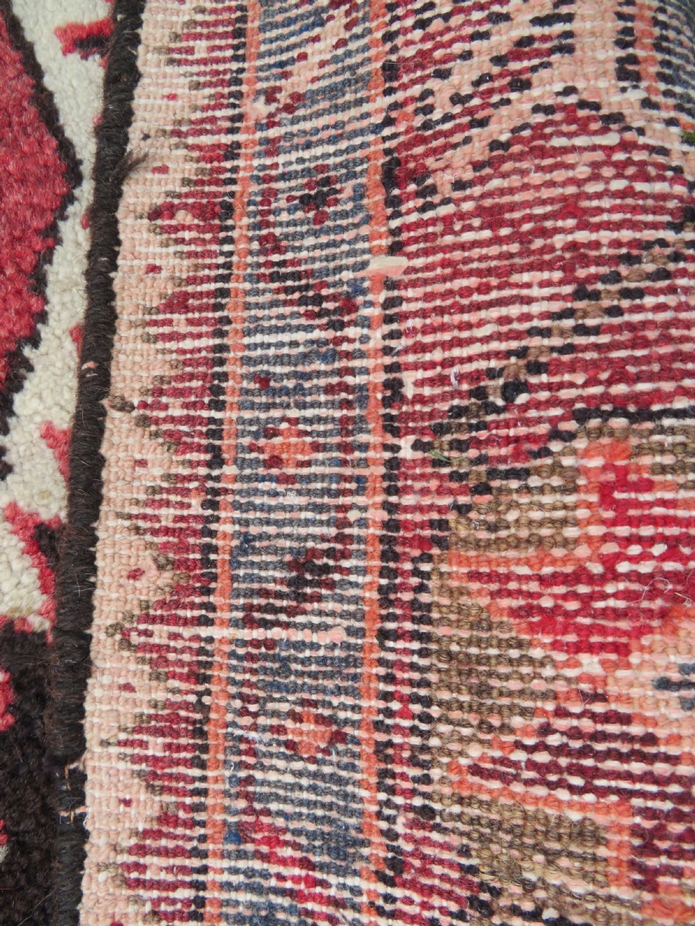A rectangular hand-knotted North West Persian Kurdish wool rug featuring a central crimson diamond medallion surrounded by geometric motifs on a dark brown field with decorative borders. View XIII