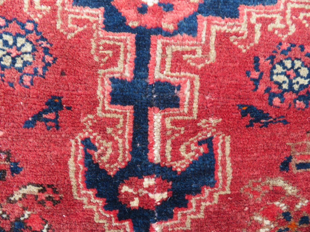 An antique Persian Malayer hand-knotted wool rug featuring a red central field, stepped navy medallion, ivory spandrels, and geometric floral borders. View VI