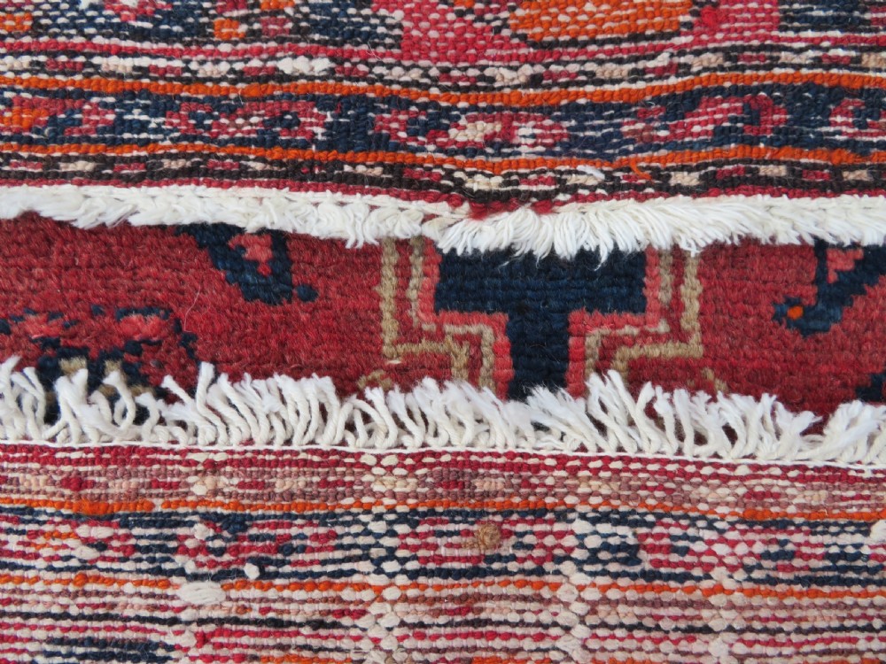 An antique Persian Malayer hand-knotted wool rug featuring a red central field, stepped navy medallion, ivory spandrels, and geometric floral borders. View XVI