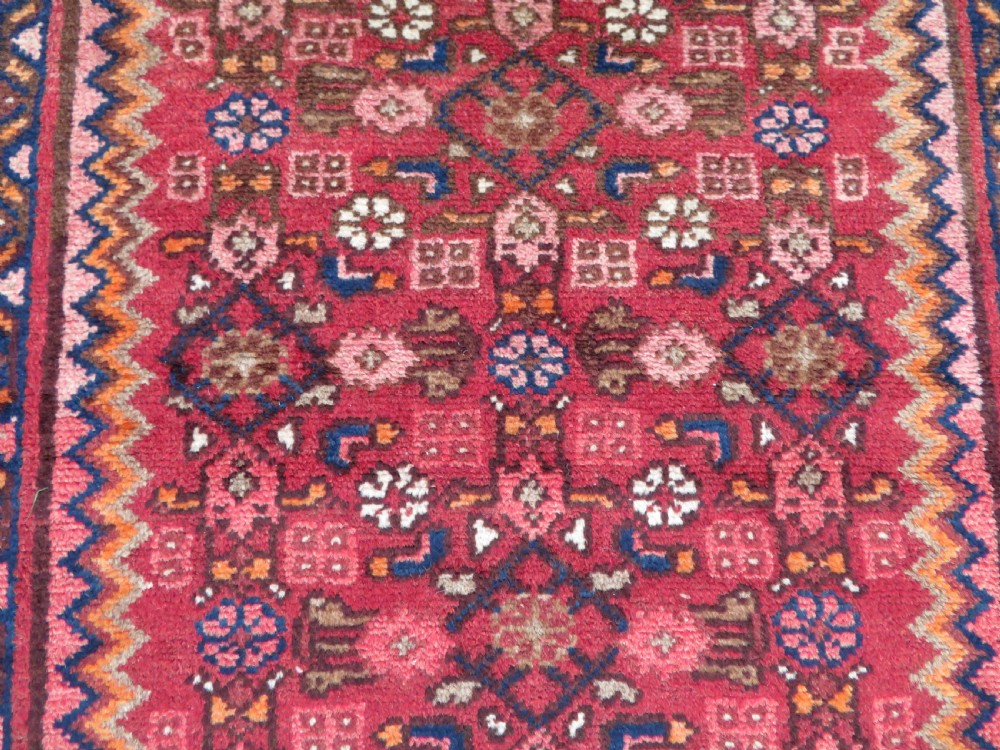 An antique Persian Sanjan Hamadan wool rug runner featuring a central diamond medallion surrounded by geometric motifs in red, cream, and navy blue. View III