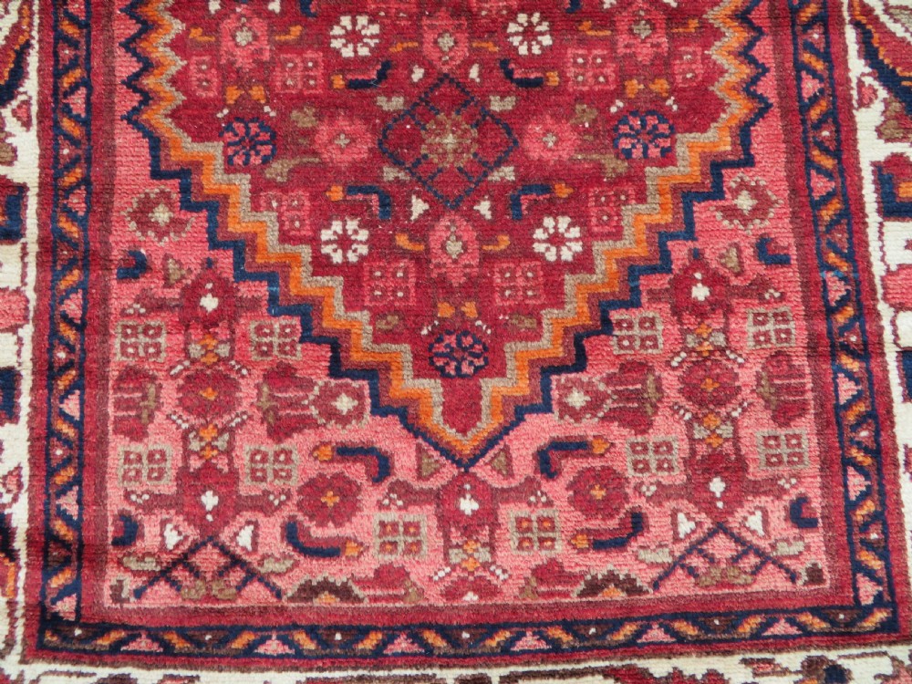 An antique Persian Sanjan Hamadan wool rug runner featuring a central diamond medallion surrounded by geometric motifs in red, cream, and navy blue. View IV