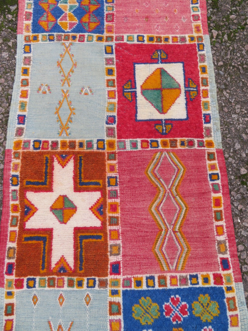 An extra long and narrow handwoven Moroccan Berber runner rug featuring geometric panels in pink, light blue, yellow, and navy with fringed ends. View VI