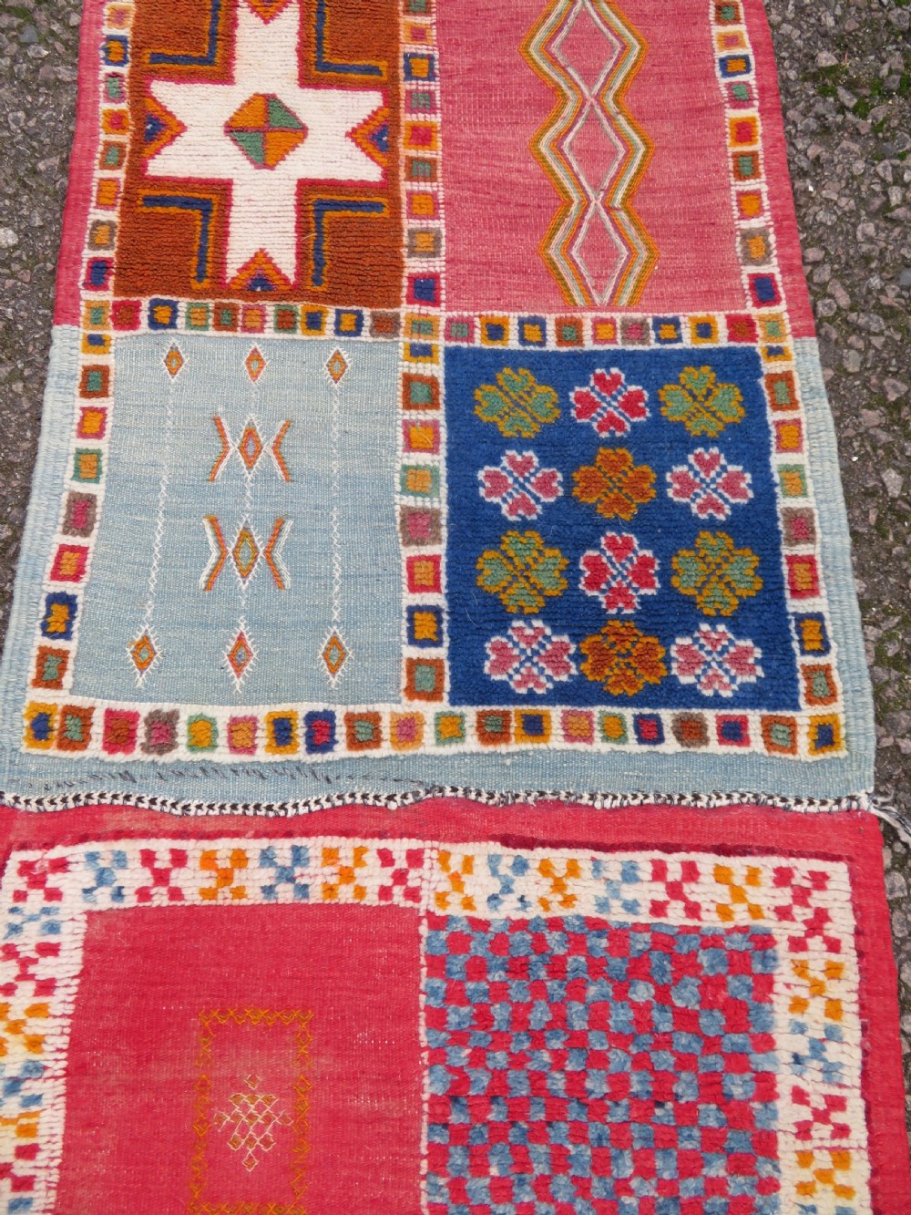 An extra long and narrow handwoven Moroccan Berber runner rug featuring geometric panels in pink, light blue, yellow, and navy with fringed ends. View VII