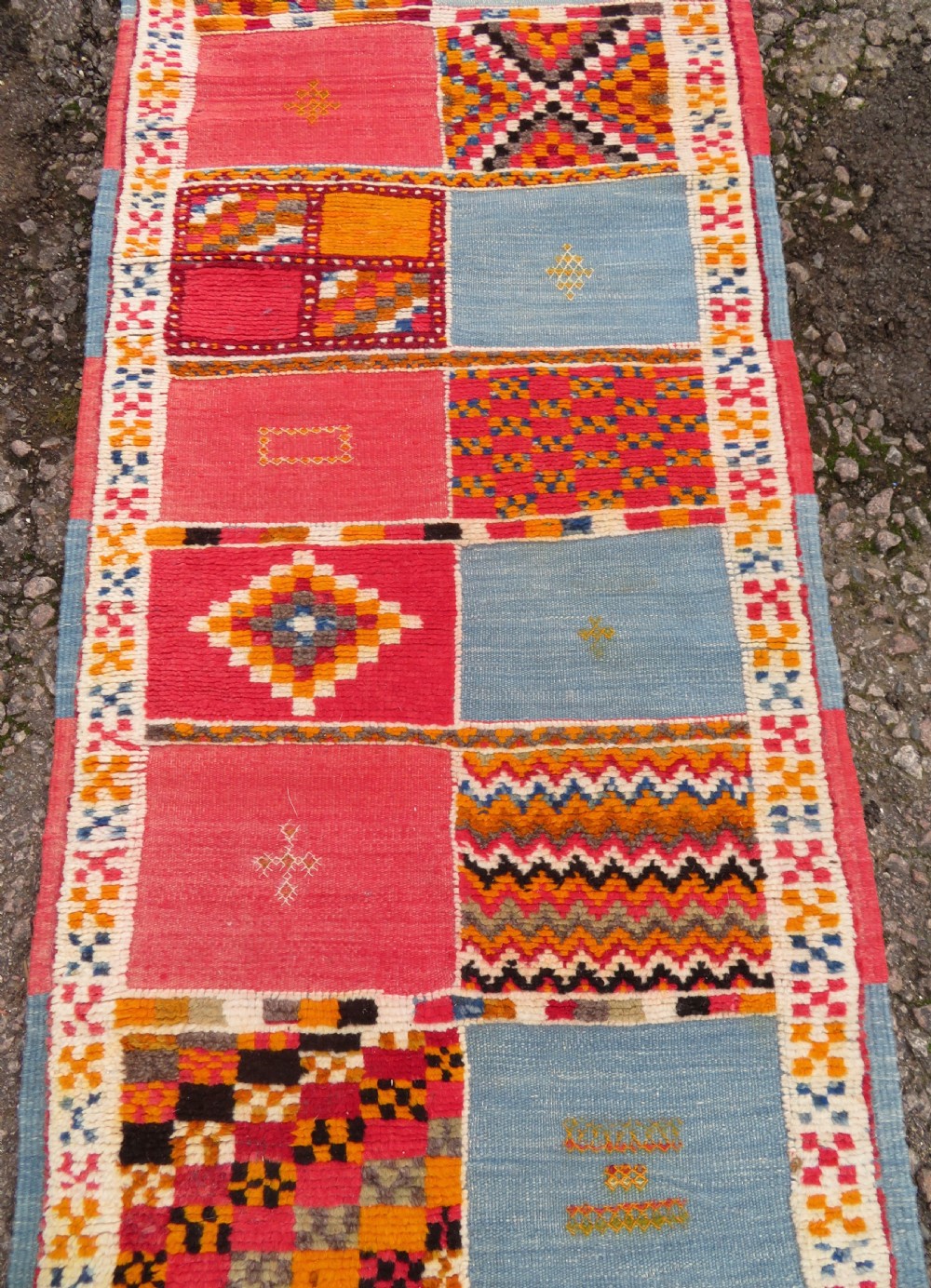 An extra long and narrow handwoven Moroccan Berber runner rug featuring geometric panels in pink, light blue, yellow, and navy with fringed ends. View IX