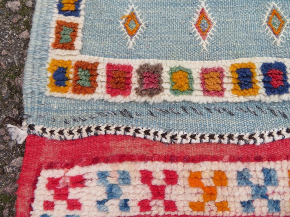 An extra long and narrow handwoven Moroccan Berber runner rug featuring geometric panels in pink, light blue, yellow, and navy with fringed ends. View XV