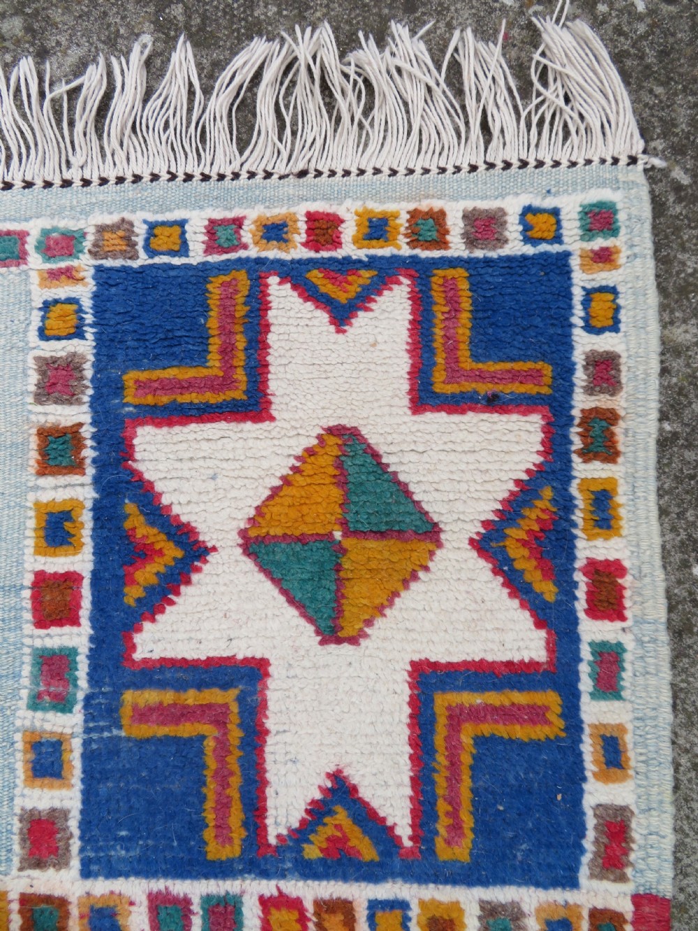 An extra long and narrow handwoven Moroccan Berber runner rug featuring geometric panels in pink, light blue, yellow, and navy with fringed ends. View XVII