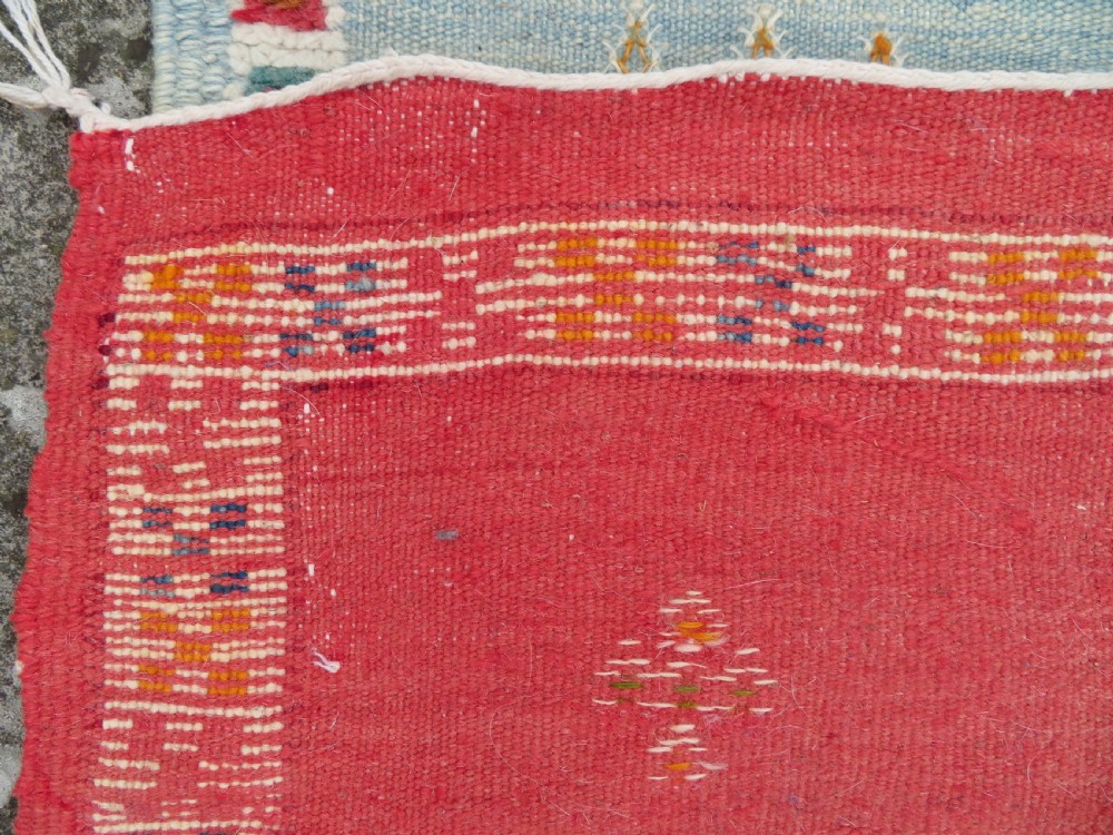 An extra long and narrow handwoven Moroccan Berber runner rug featuring geometric panels in pink, light blue, yellow, and navy with fringed ends. View XIX
