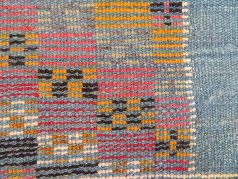 An extra long and narrow handwoven Moroccan Berber runner rug featuring geometric panels in pink, light blue, yellow, and navy with fringed ends. View XX