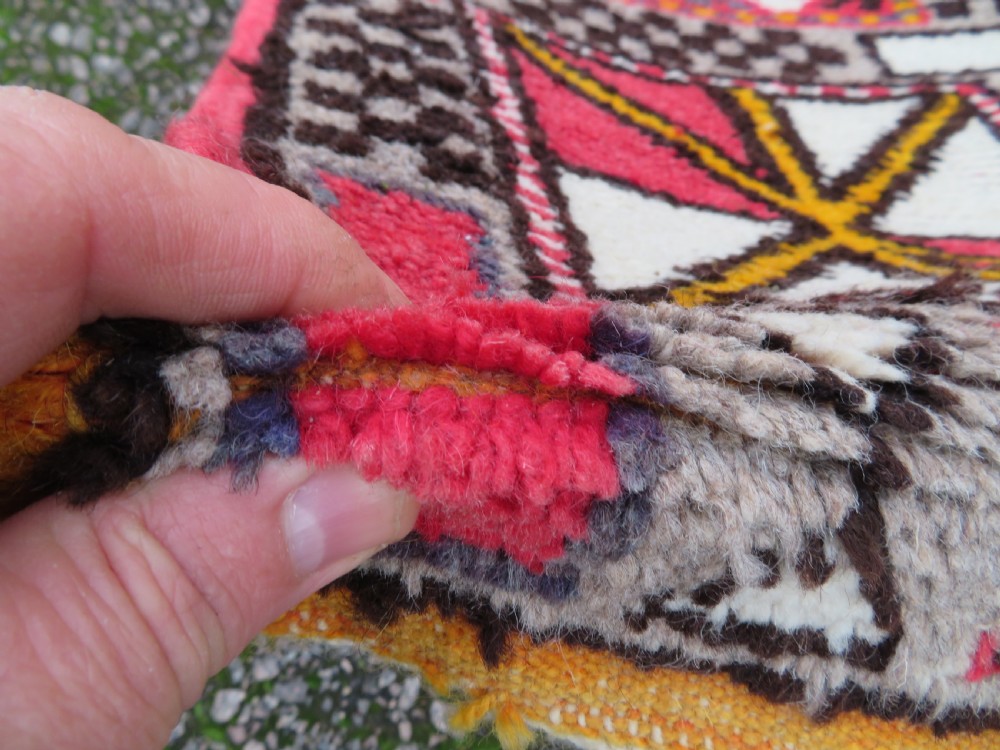 A rectangular hand-knotted Moroccan Berber wool rug featuring geometric patchwork panels in pink, yellow, black, grey, and white with fringed ends. View IX