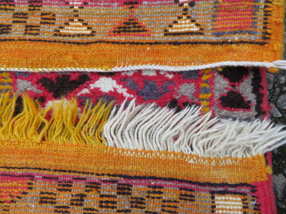 A rectangular hand-knotted Moroccan Berber wool rug featuring geometric patchwork panels in pink, yellow, black, grey, and white with fringed ends. View XII