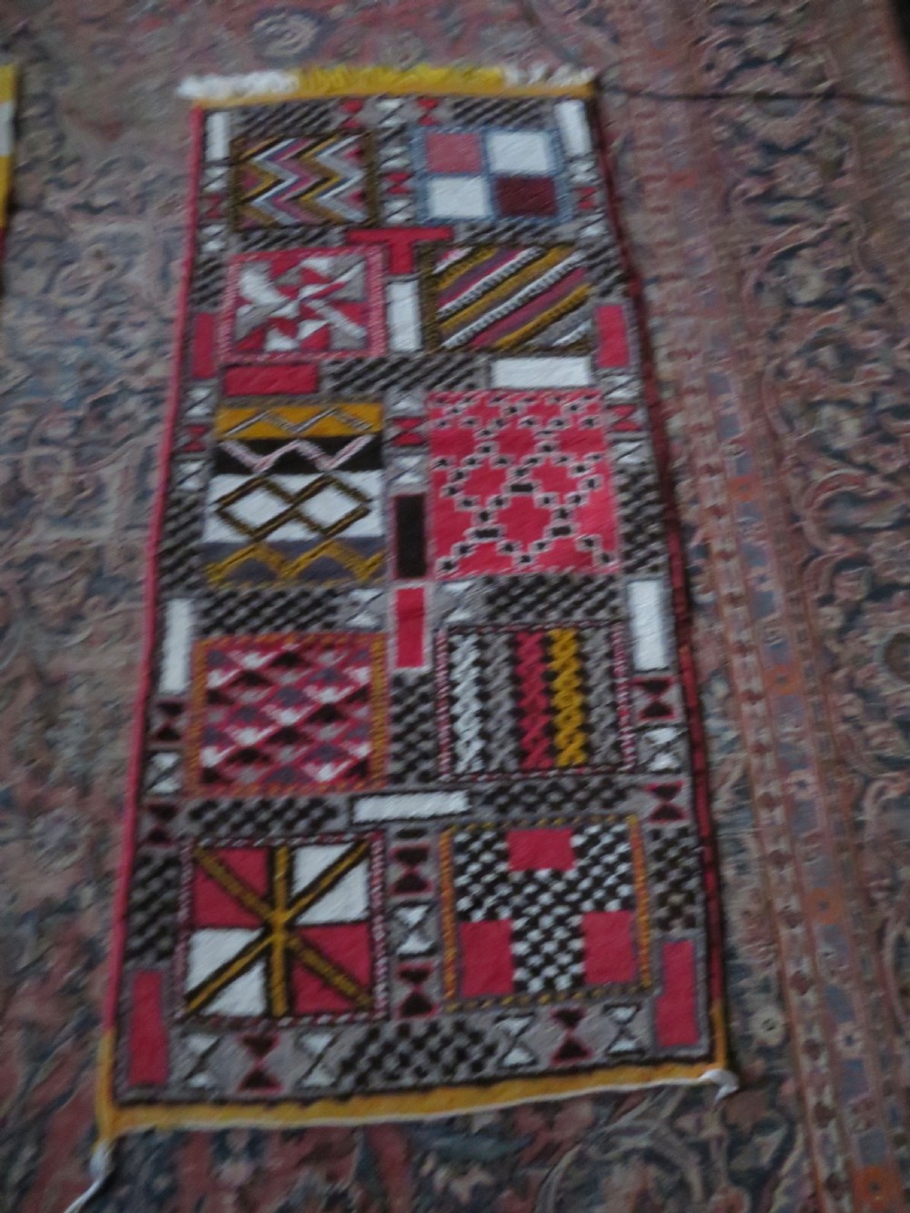 A rectangular hand-knotted Moroccan Berber wool rug featuring geometric patchwork panels in pink, yellow, black, grey, and white with fringed ends. View XIV