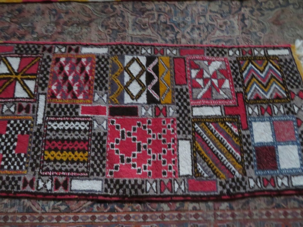 A rectangular hand-knotted Moroccan Berber wool rug featuring geometric patchwork panels in pink, yellow, black, grey, and white with fringed ends. View XV