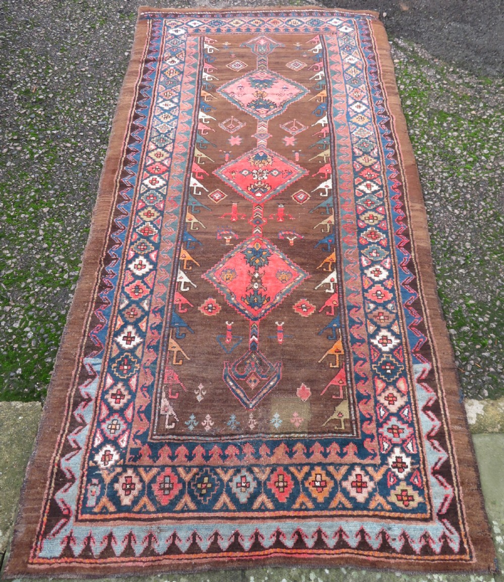 An antique Kurdish hand-knotted long wool rug featuring three central red diamond medallions surrounded by geometric tribal borders on a dark brown field. View II