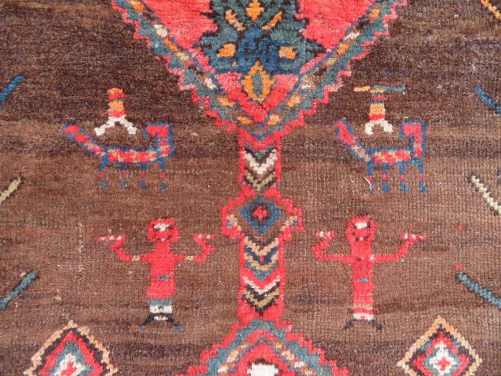 An antique Kurdish hand-knotted long wool rug featuring three central red diamond medallions surrounded by geometric tribal borders on a dark brown field. View V