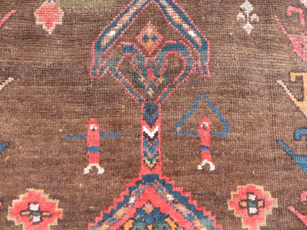An antique Kurdish hand-knotted long wool rug featuring three central red diamond medallions surrounded by geometric tribal borders on a dark brown field. View VI