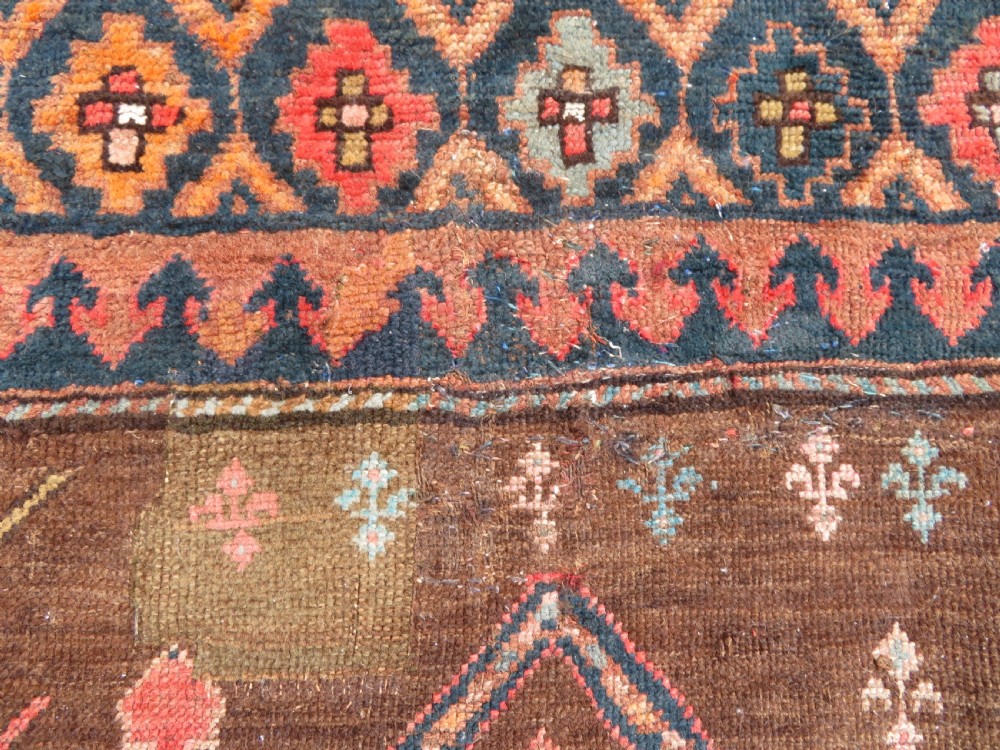 An antique Kurdish hand-knotted long wool rug featuring three central red diamond medallions surrounded by geometric tribal borders on a dark brown field. View VII