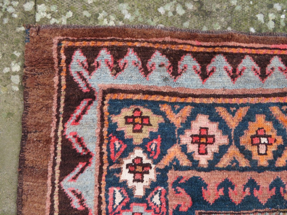 An antique Kurdish hand-knotted long wool rug featuring three central red diamond medallions surrounded by geometric tribal borders on a dark brown field. View VIII