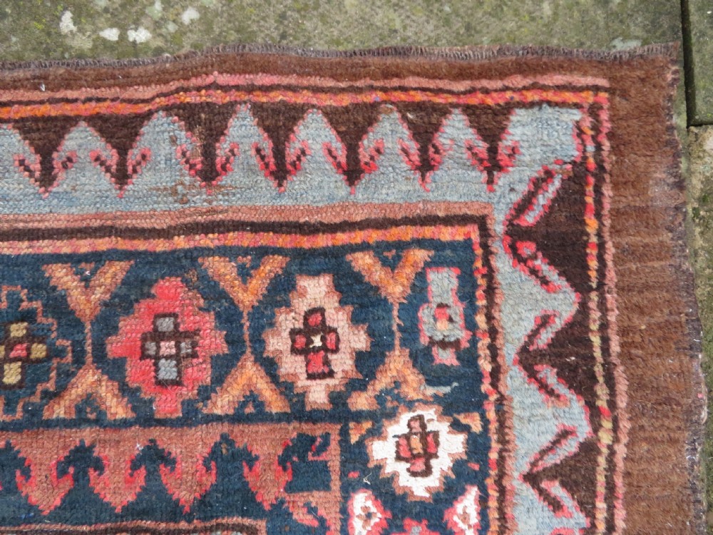 An antique Kurdish hand-knotted long wool rug featuring three central red diamond medallions surrounded by geometric tribal borders on a dark brown field. View IX