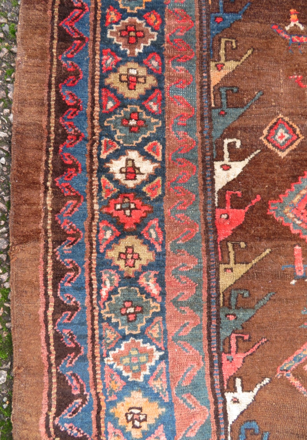 An antique Kurdish hand-knotted long wool rug featuring three central red diamond medallions surrounded by geometric tribal borders on a dark brown field. View XII