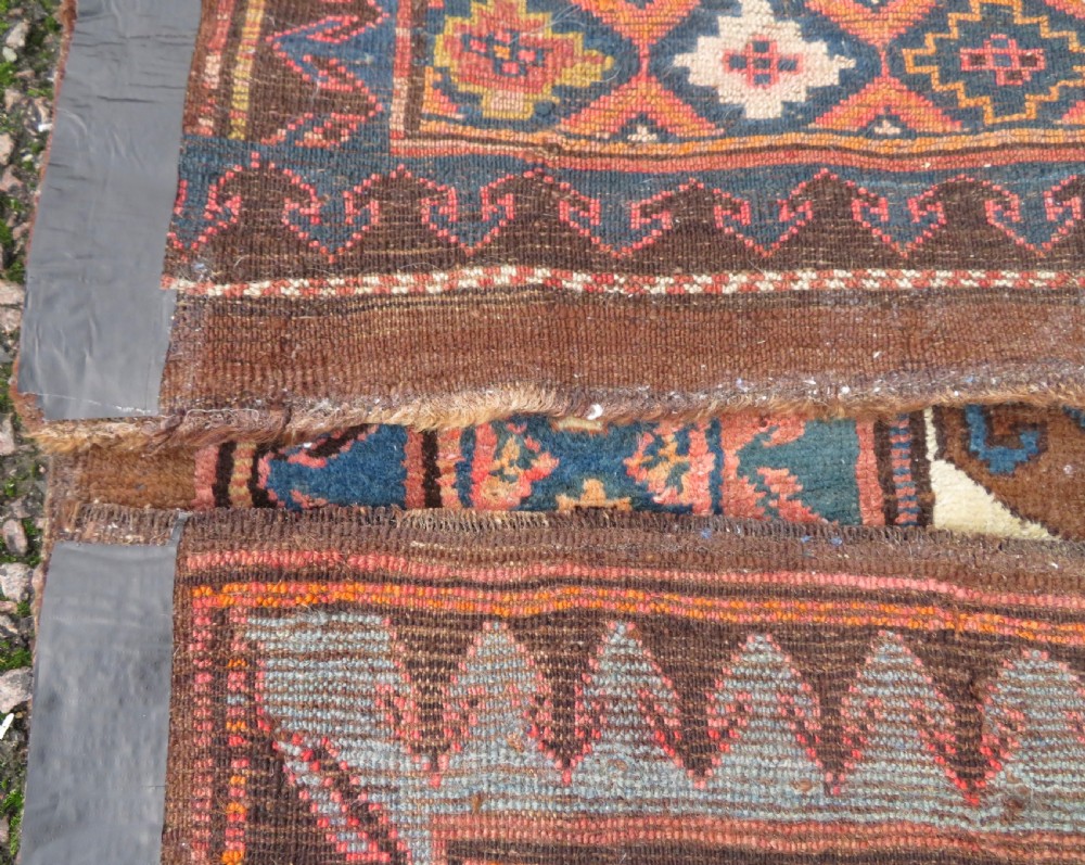 An antique Kurdish hand-knotted long wool rug featuring three central red diamond medallions surrounded by geometric tribal borders on a dark brown field. View XV