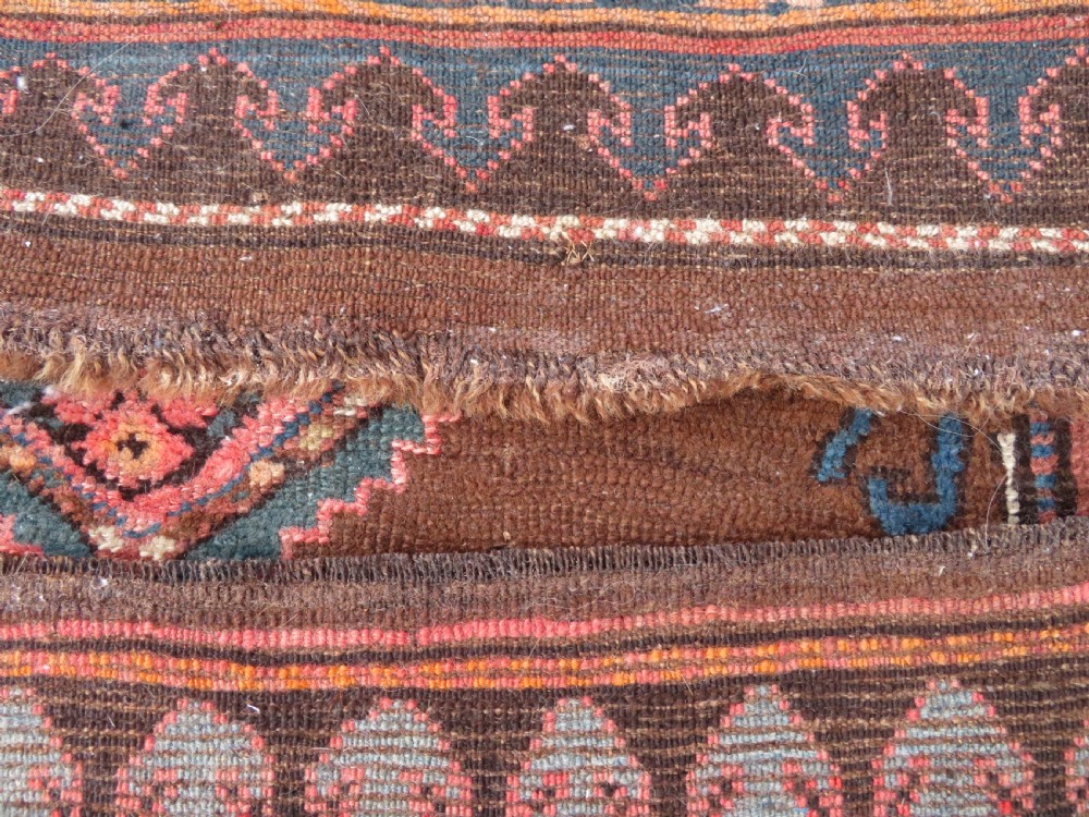 An antique Kurdish hand-knotted long wool rug featuring three central red diamond medallions surrounded by geometric tribal borders on a dark brown field. View XVI