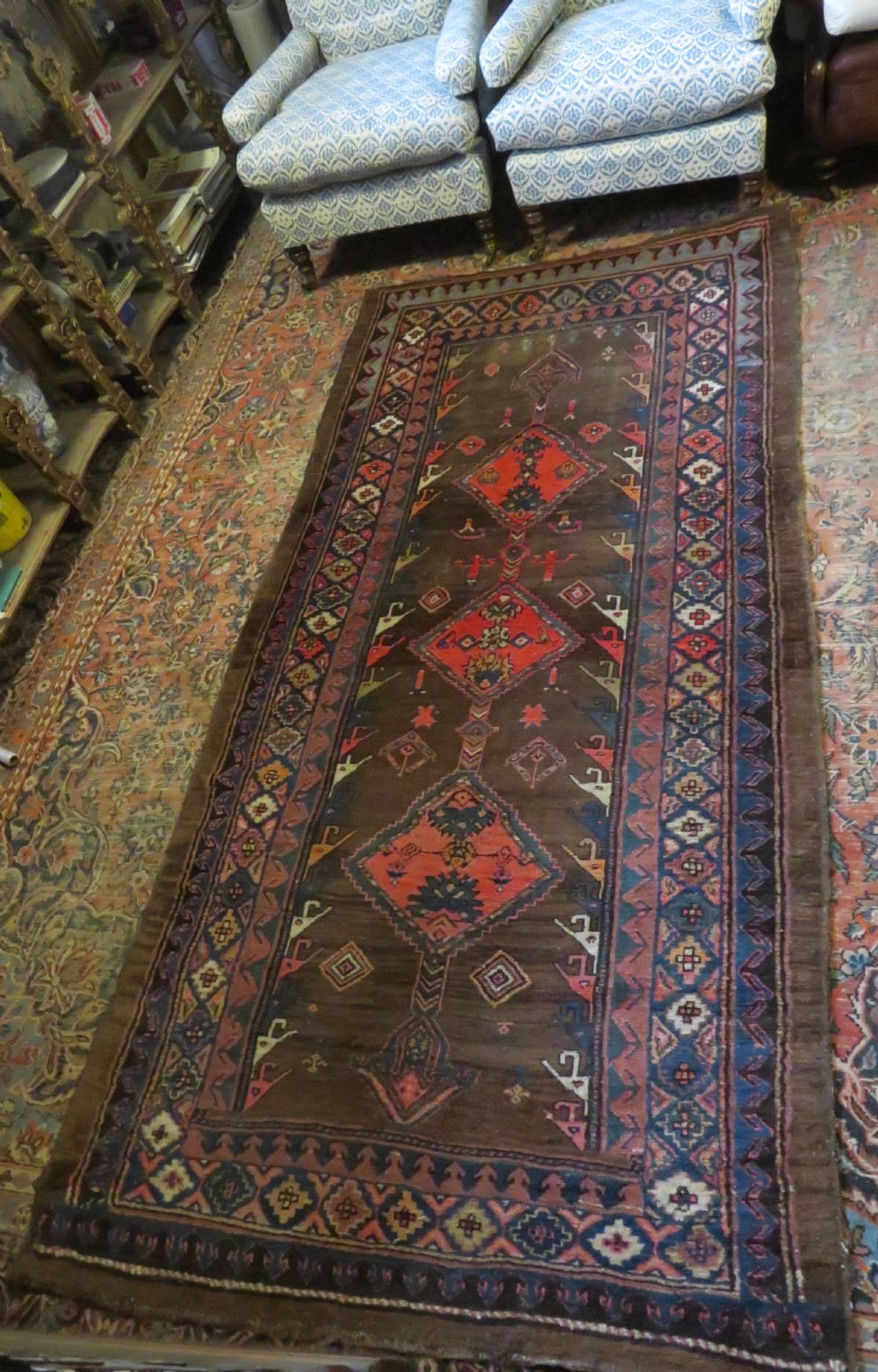 An antique Kurdish hand-knotted long wool rug featuring three central red diamond medallions surrounded by geometric tribal borders on a dark brown field. View XVII