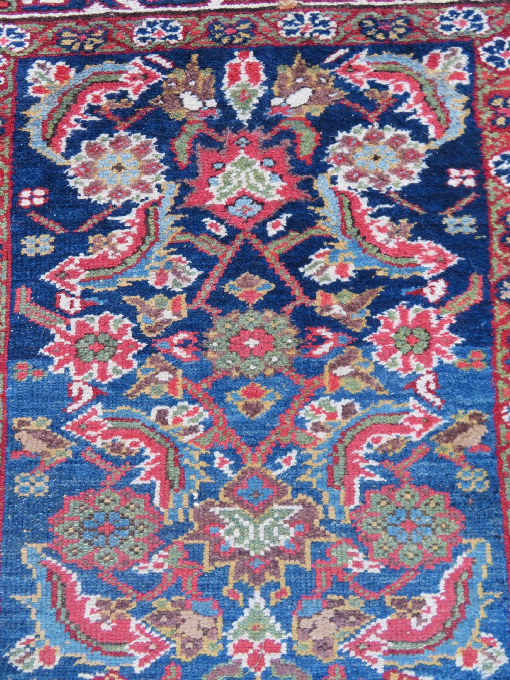 A long, narrow antique Persian Fereghan runner rug featuring detailed floral lattice motifs on a deep navy field framed by multi-tiered terracotta red and cream patterned borders. View V