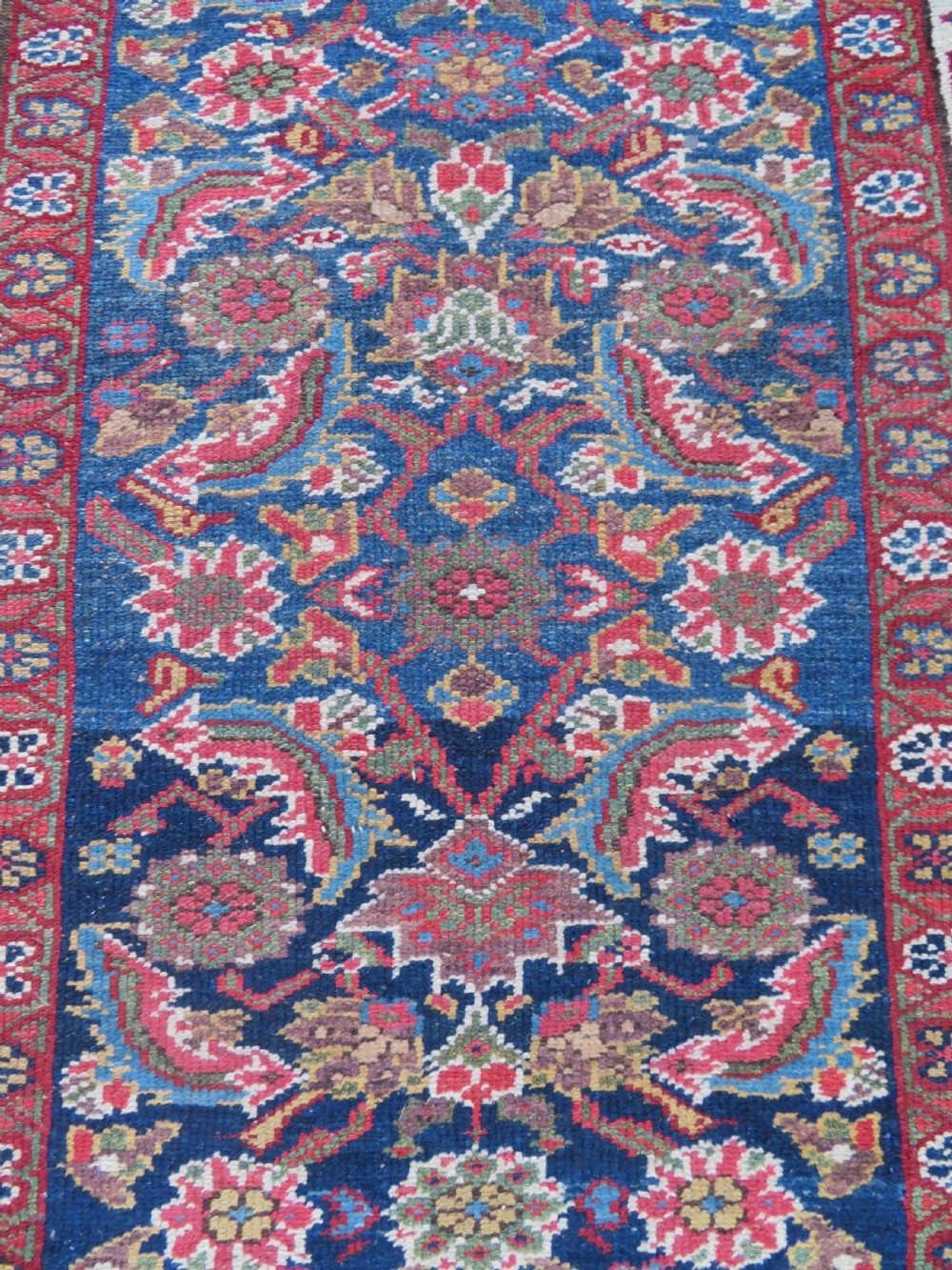 A long, narrow antique Persian Fereghan runner rug featuring detailed floral lattice motifs on a deep navy field framed by multi-tiered terracotta red and cream patterned borders. View VI