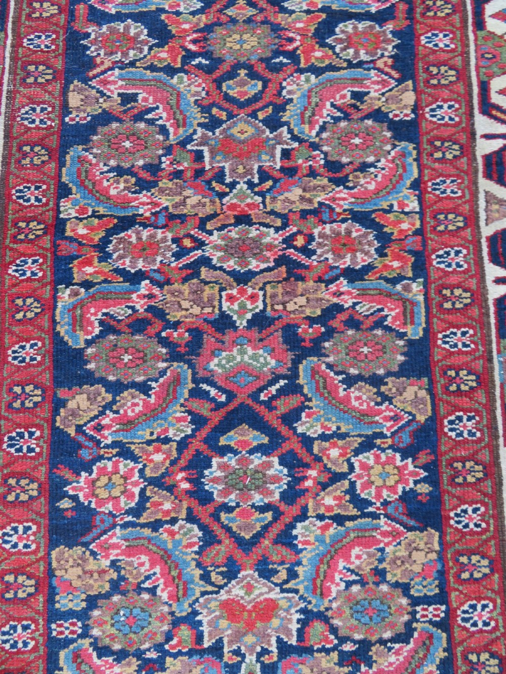 A long, narrow antique Persian Fereghan runner rug featuring detailed floral lattice motifs on a deep navy field framed by multi-tiered terracotta red and cream patterned borders. View VII