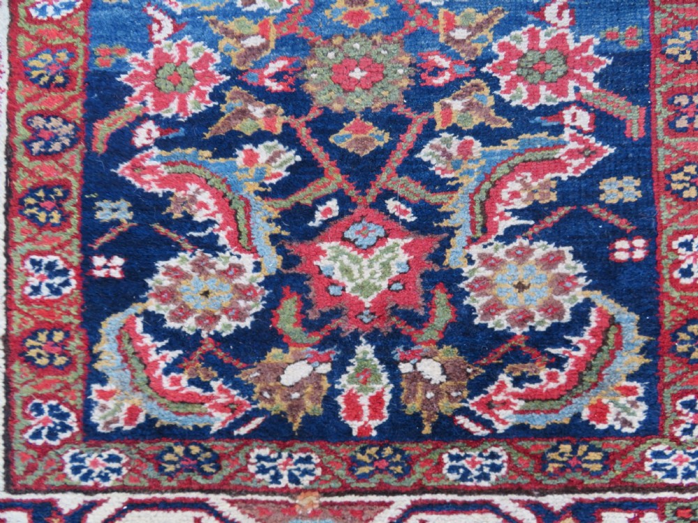 A long, narrow antique Persian Fereghan runner rug featuring detailed floral lattice motifs on a deep navy field framed by multi-tiered terracotta red and cream patterned borders. View X