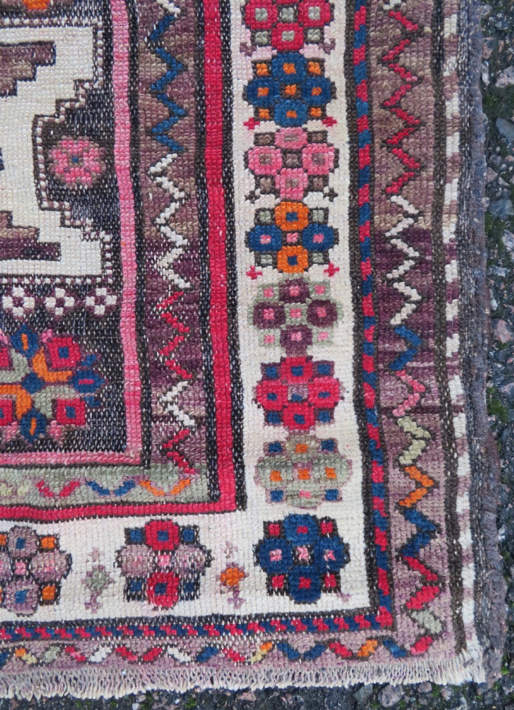 An antique hand-knotted Caucasian Lesghi wool rug featuring geometric star medallions in red, blue, cream, and brown surrounded by decorative pattern borders. View VI