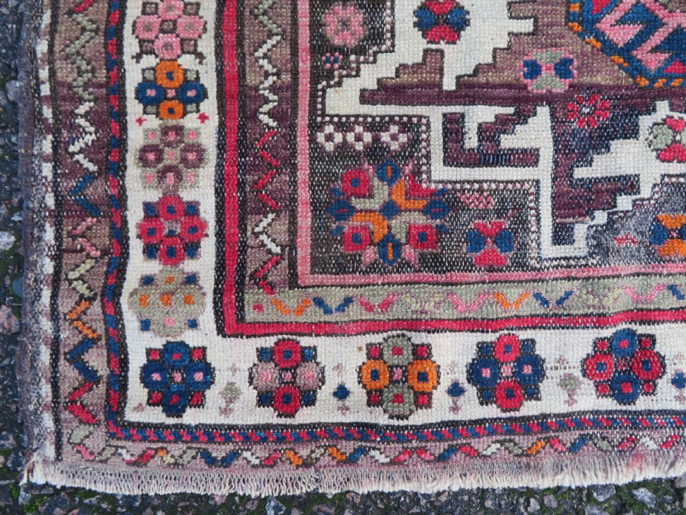 An antique hand-knotted Caucasian Lesghi wool rug featuring geometric star medallions in red, blue, cream, and brown surrounded by decorative pattern borders. View VII