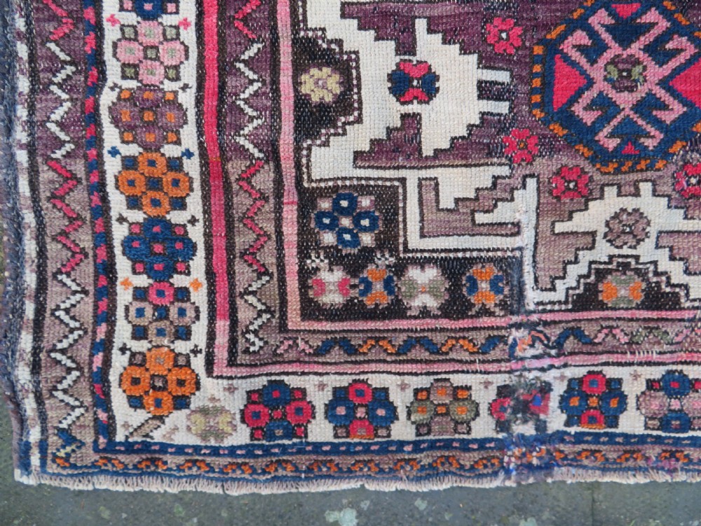 An antique hand-knotted Caucasian Lesghi wool rug featuring geometric star medallions in red, blue, cream, and brown surrounded by decorative pattern borders. View VIII