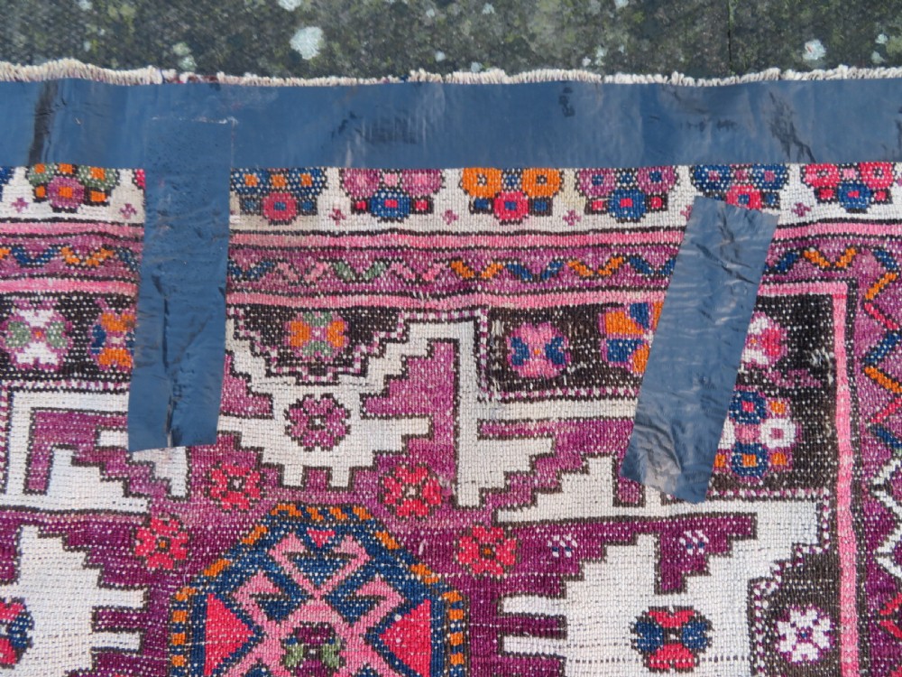 An antique hand-knotted Caucasian Lesghi wool rug featuring geometric star medallions in red, blue, cream, and brown surrounded by decorative pattern borders. View XVI