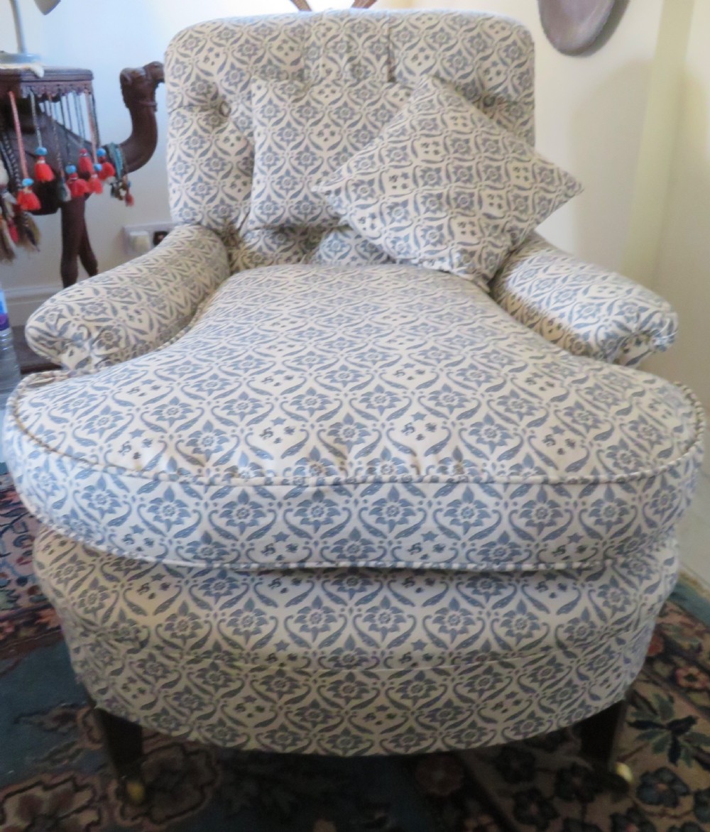 A deep upholstered easy armchair featuring blue and cream patterned fabric with button-back detailing and matching loose cushions.