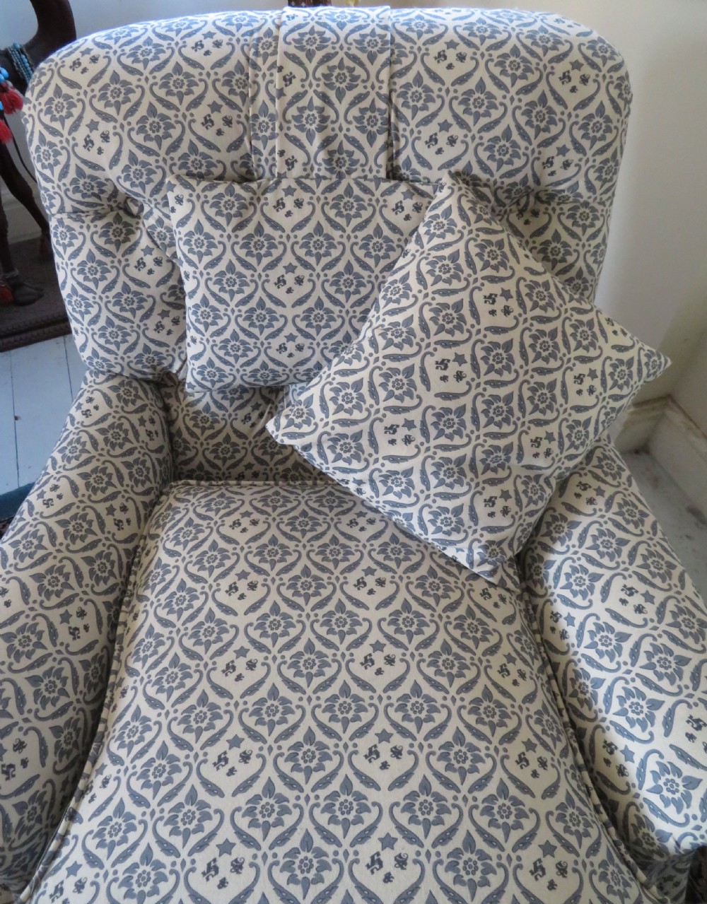 A deep upholstered easy armchair featuring blue and cream patterned fabric with button-back detailing and matching loose cushions. View V