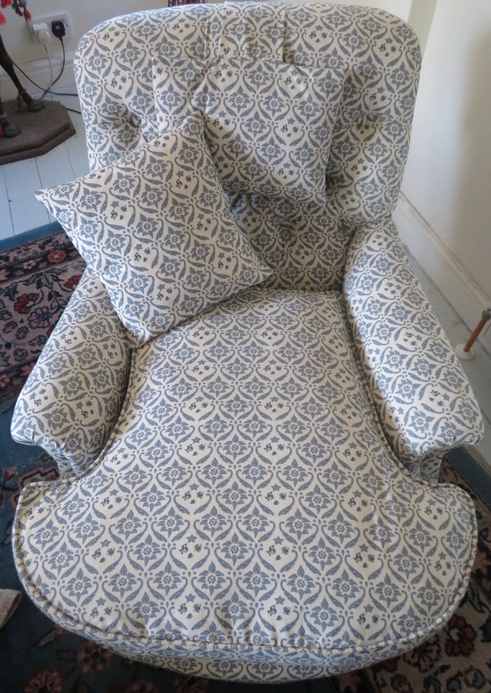 A deep upholstered easy armchair featuring blue and cream patterned fabric with button-back detailing and matching loose cushions. View VII