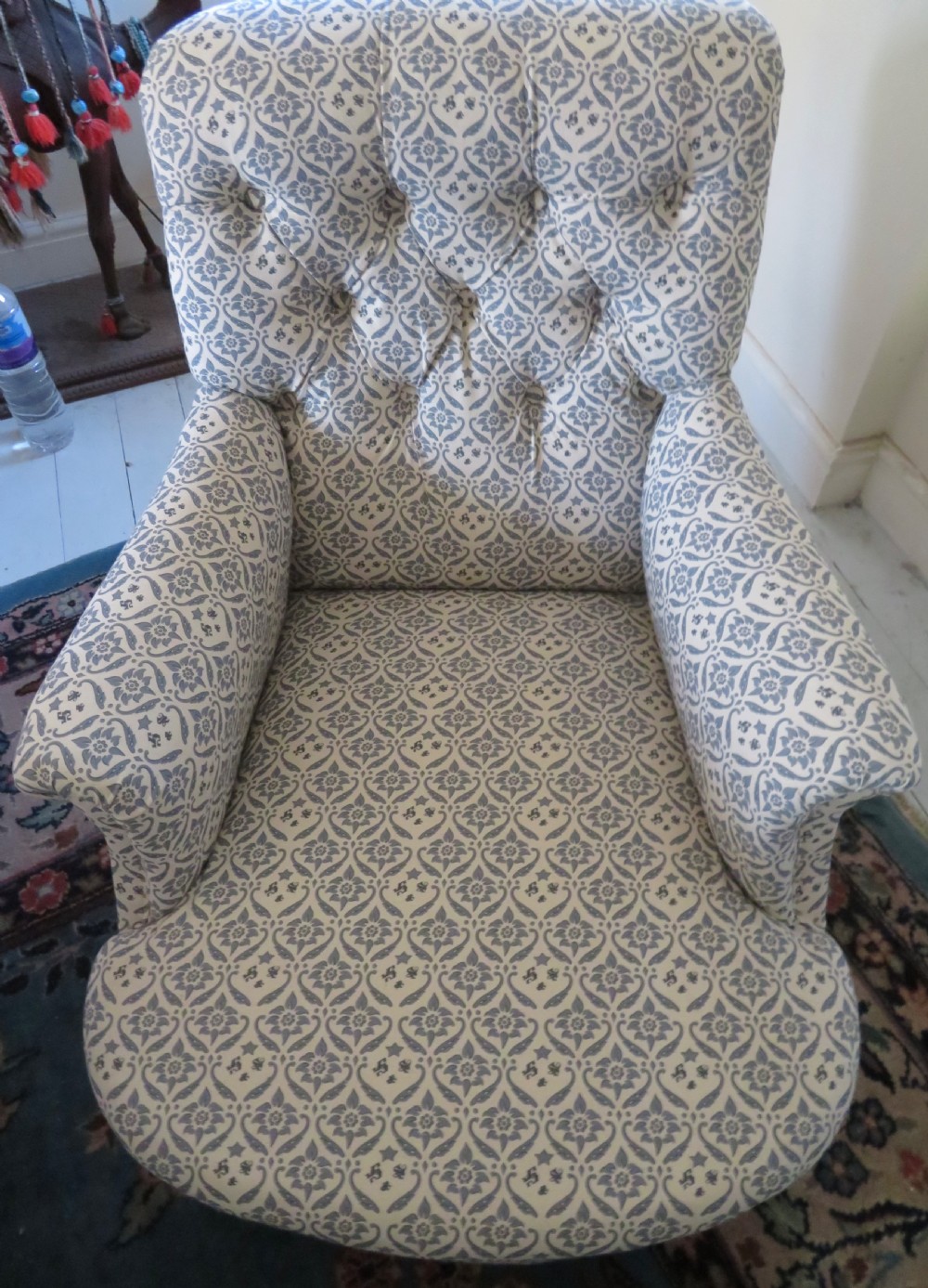 A deep upholstered easy armchair featuring blue and cream patterned fabric with button-back detailing and matching loose cushions. View X