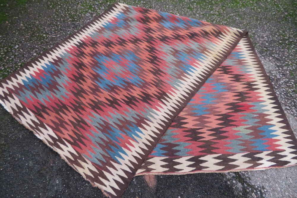 A long handwoven wool kilim runner displaying repeated serrated geometric diamond patterns in terracotta, blue, cream, and brown. View XI