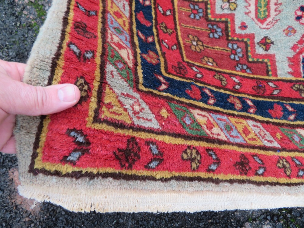 A hand-knotted Turkish village rug featuring central geometric stepped medallions in red, yellow, and navy on a cream field surrounded by decorative borders. View IV