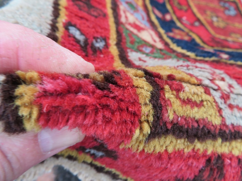 A hand-knotted Turkish village rug featuring central geometric stepped medallions in red, yellow, and navy on a cream field surrounded by decorative borders. View V